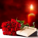 Rosen und Geschenkbox vor Kerzenschein