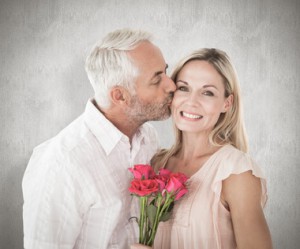 Affectionate man kissing his wife on the cheek with roses